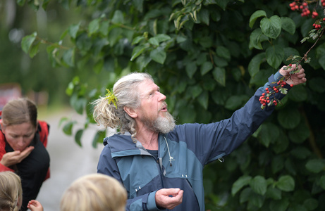 Ein Mann erklärt Interessierten etwas über Obstbäume – vermutlich Teil einer Hofführung zu ökologischer Landwirtschaft.