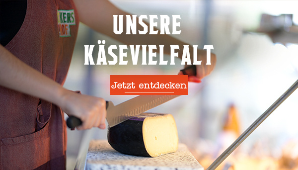 KI generiert: Eine Person schneidet Käse. Text: "UNSERE KÄSEVIELFALT Jetzt entdecken".