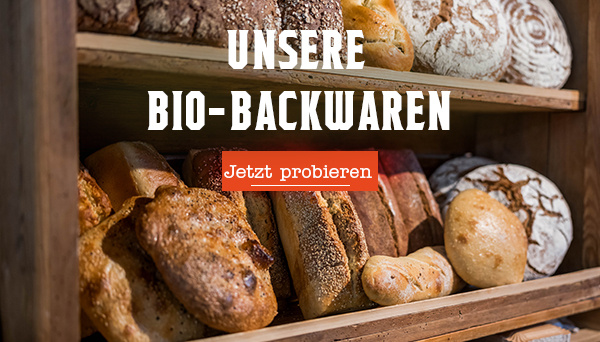 KI-generierte Beschreibung: Hauptinhalt: Bio-Backwaren in Holzkiste. Text: "UNSERE BIO-BACKWAREN Jetzt probieren".