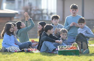 KI generiert: Kinder picknicken in der Sonne mit einem Korb voller Obst.