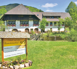 Ein traditionelles Haus und ein Schild mit: "Urlaub auf dem Ramsteinerhof, Hofkäserei".