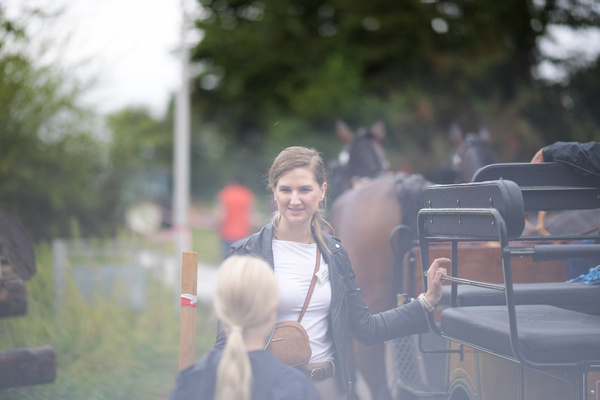 Eine Frau steht neben einem Pferd und lächelt – vermutlich nach einer Kutschfahrt, ein beliebtes Angebot beim Hoffest.