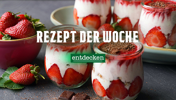 Nahaufnahme einer cremigen Suppe, garniert mit Kräutern und Pilzen, in einer Schüssel. Im Hintergrund liegen Zwiebeln. Text im Bild: „Rezept der Woche – entdecken