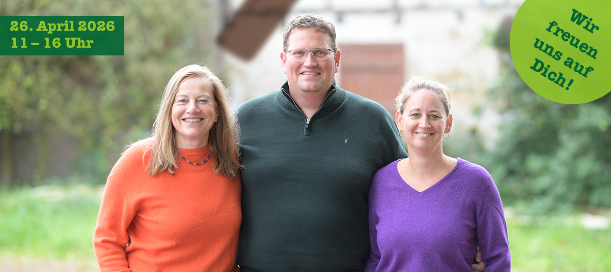 KI generiert: Drei Personen lächeln in die Kamera, Text: "26. April 2026, 11 - 16 Uhr. Wir freuen uns auf Dich!"