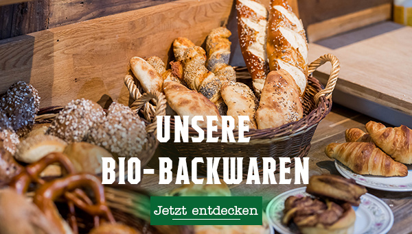 KI generiert: Körbe voller Brot und Gebäck. Text: "UNSERE BIO-BACKWAREN. Jetzt entdecken".